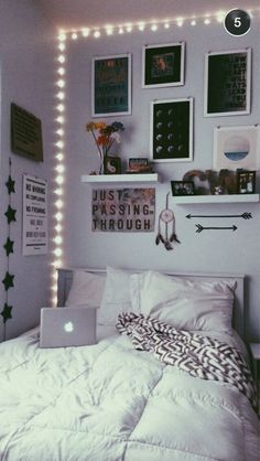 a white bed sitting in a bedroom next to a wall with pictures and lights on it