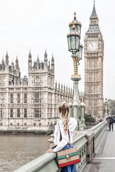 a woman is standing on a bridge looking at the big ben clock tower