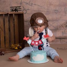 a baby boy wearing a pilot's hat and eating cake