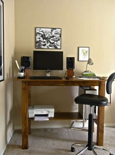 a desk with a computer and speakers on it in front of a wall mounted poster