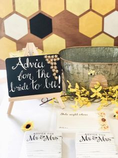 a table topped with cards and flowers next to a bucket filled with honeybees