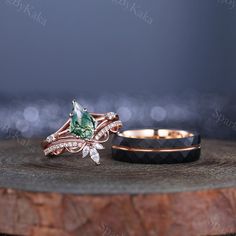 two wedding rings with green and white stones on top of a wooden table next to each other