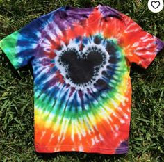 a tie - dyed shirt with a heart in the center is laying on some grass