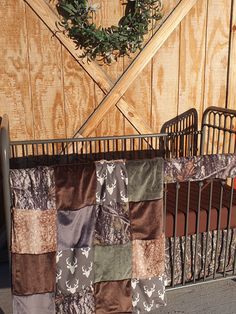 a baby crib with a blanket on top of it next to a wooden wall