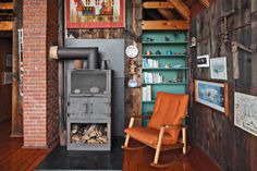 a room with a chair, bookshelf and wood burning stove