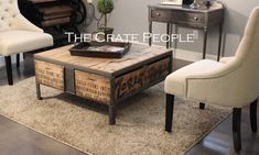 a living room with two chairs and a coffee table in front of a wall that reads the crate people