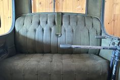 an old green couch sitting in the back of a truck with wood paneling on it