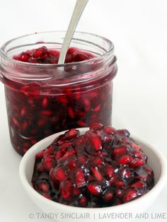 cranberry sauce in a white bowl with a spoon next to it on a white surface