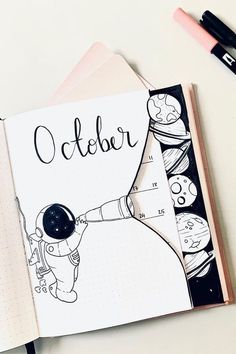 an open notebook with the word october written on it next to a pen and marker