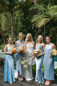 a group of women standing next to each other on a wooden platform in front of trees