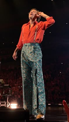 a man standing on top of a stage with his hands to his face while holding a microphone