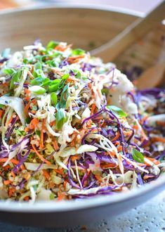 a white bowl filled with coleslaw slaw and carrots next to a wooden spoon