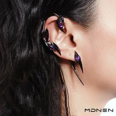 a woman wearing ear piercings with purple stones on her ears and the words monen written in black ink