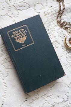 a green book sitting on top of a table next to a gold locke and chain