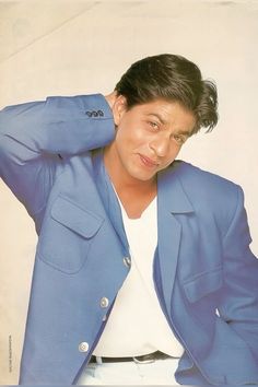 a man in a blue blazer and white shirt is posing for the camera with his hands on his head