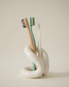 three toothbrushes are in a white holder