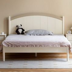 a white bed with a teddy bear sitting on top of it