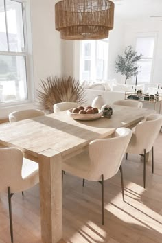 a dining room table with white chairs and a bowl of food on it