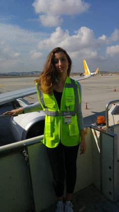 a woman in safety vest standing at an airport gate