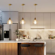 three lights hanging from the ceiling above a kitchen island with stools and countertop