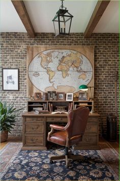 an old world map hangs on the wall above a desk with a chair and lamp