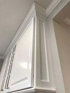 the corner of a kitchen cabinet with white paint and trim on it's doors