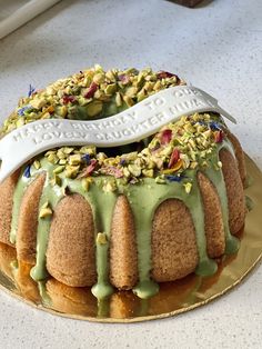 a bundt cake with green icing and nuts on top sitting on a plate