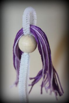 a purple and white bead hanging from a string