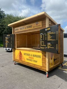 a hot dog stand with menus and prices on the outside, in a parking lot