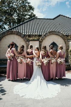 a group of women standing next to each other in front of a building with flowers