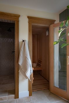 a wooden sauna in the corner of a bathroom with tiled flooring and walls