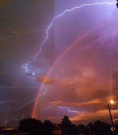 a rainbow is seen in the sky with lightning