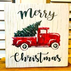 a red truck with a christmas tree in the back is painted on a wooden sign