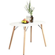 a white table with two wooden legs and some fruit on the plate next to it