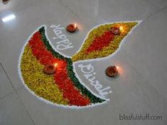 a decorated floor with lit candles and flowers on it that says happy diwali