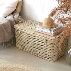 a wicker basket sitting on top of a table next to a bed