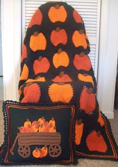 a chair with two pillows on top of it and an orange pumpkin afghan next to it