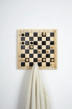 a black and white checkered board mounted on a wall with a cloth hanging from it