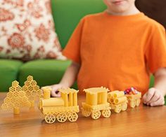 a young boy playing with toy train set on the wooden table in front of green couch