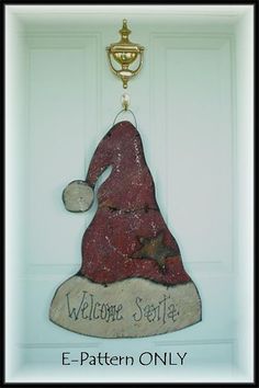 a welcome sign hanging on the front door with a santa hat and star ornament