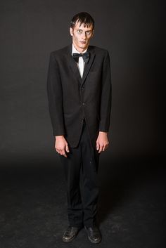 a man in a tuxedo is posing for the camera with his hands on his hips