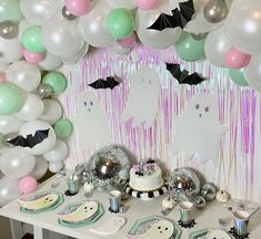 a table topped with lots of balloons next to a wall covered in white and pink decorations