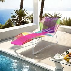 a colorful lounge chair sitting on top of a patio next to a swimming pool and palm trees