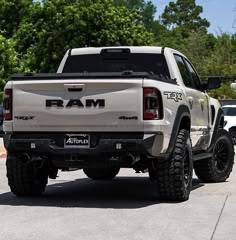 the rear end of a white ram truck parked in a parking lot next to trees