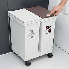 a person pushing a trash can next to a toilet in a bathroom that is white and brown