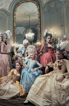 a group of people dressed up in fancy dresses and headpieces sitting next to each other