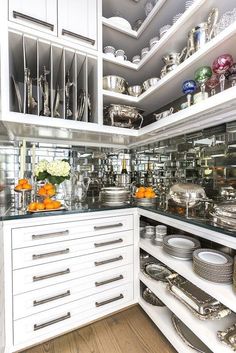 a kitchen filled with lots of white cupboards and silverware on top of wooden flooring