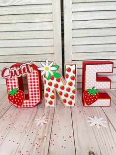 the letters are made out of wood and have strawberries on them with polka dots