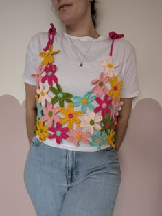 a woman in jeans and a t - shirt with crocheted flowers on it