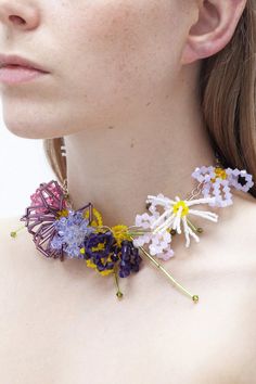 a woman wearing a necklace with flowers on it